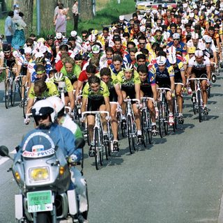 Cyclists racing in a large group on a road.