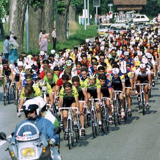 Cyclists racing in a large group on a road.
