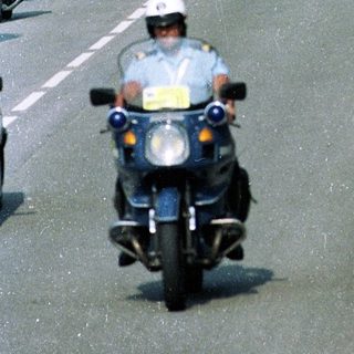 Motorcade with police escort on city road.