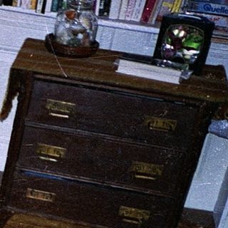 Teen holding game controller, lounging drowsily in armchair.