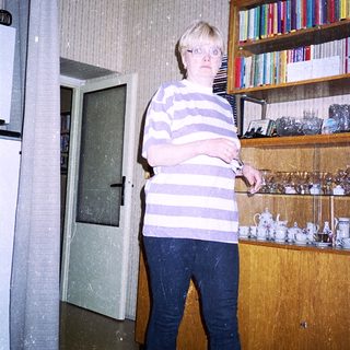 Person standing indoors holding a knife near kitchen shelves.