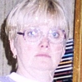 Person standing indoors holding a knife near kitchen shelves.