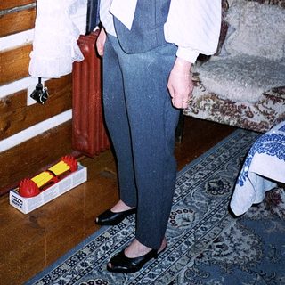 Woman in vintage-style vest and pants indoors.