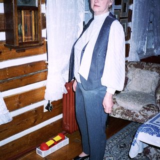 Woman in vintage-style vest and pants indoors.