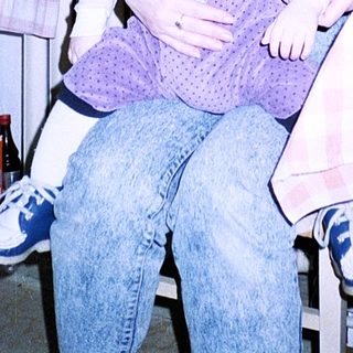 A woman holding a baby indoors near a poster of the Eiffel Tower.