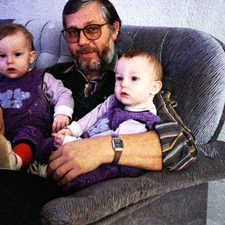 Man holding two young children on a couch.