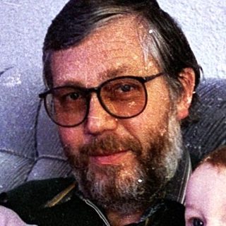 Man holding two young children on a couch.
