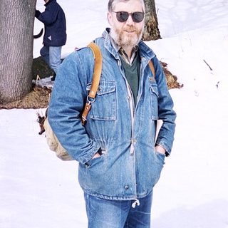 Man in winter gear posing in snowy forest.