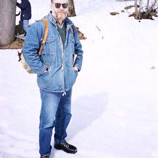 Man in winter gear posing in snowy forest.