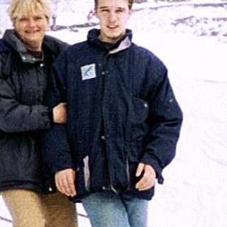 Two people standing on snow-covered ski slope.