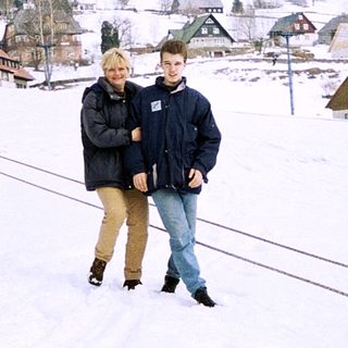 Two people standing on snow-covered ski slope.