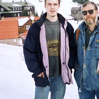 Two men posing in snowy village landscape.