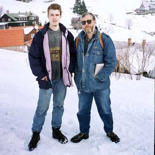 Two men posing in snowy village landscape.