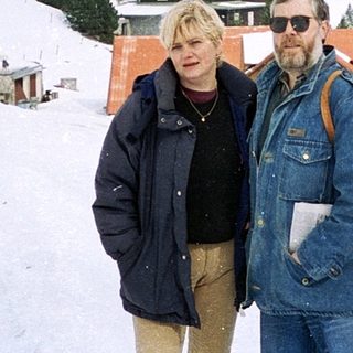 Two people posing on snowy mountain landscape.