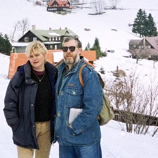 Two people posing on snowy mountain landscape.