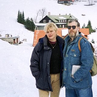 Two people posing on snowy mountain landscape.