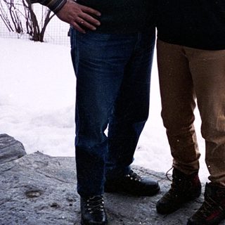 Three people posing outdoors in snowy mountainous area.