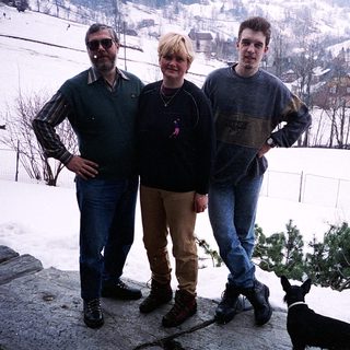 Three people posing outdoors in snowy mountainous area.