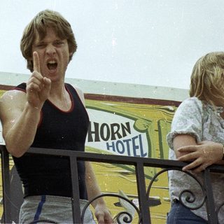 Two men reacting excitedly near a Horn Hotel.
