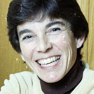 Smiling person wearing light sweater indoors.