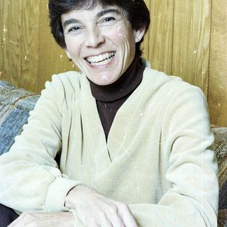 Smiling person wearing light sweater indoors.