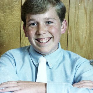 Young boy smiling in light blue dress shirt and tie.
