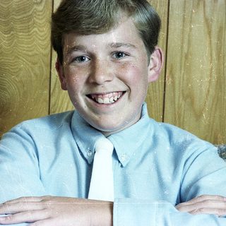 Young boy smiling in light blue dress shirt and tie.