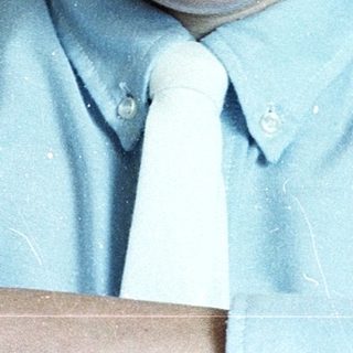 Young boy smiling in light blue dress shirt and tie.