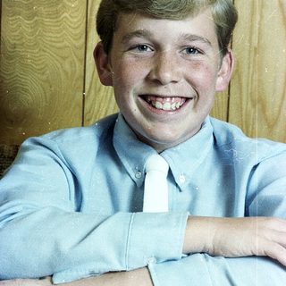 Young boy smiling in light blue dress shirt and tie.