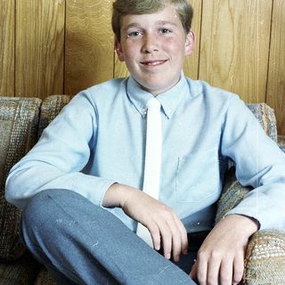 Young boy smiling in light blue shirt.