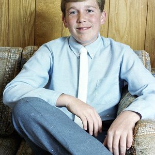 Young boy smiling in light blue shirt.