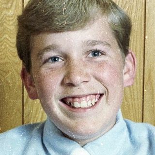 Young boy smiling in light blue shirt and tie.