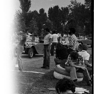 People watching military vehicle parade outdoors.