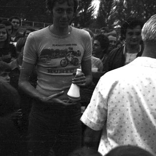 Cyclist receiving trophy from man in outdoor event.