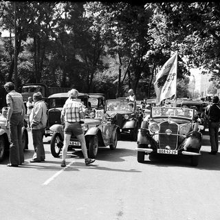 Vintage car rally with classic vehicles and spectators.