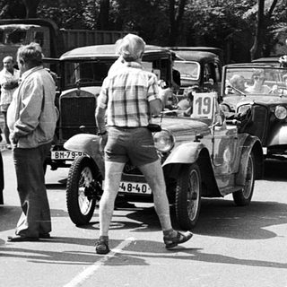 Vintage car rally with classic vehicles and spectators.