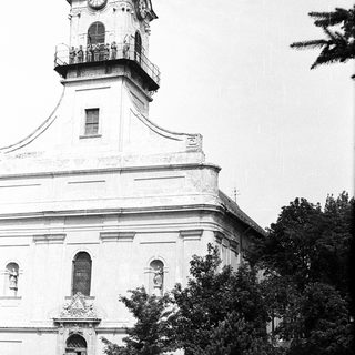 Historic church with clock tower, vintage cars, and crowd.