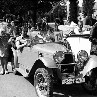 Vintage car rally with spectators and vintage vehicles.
