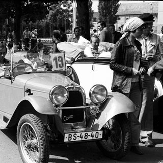 Vintage car rally with spectators and vintage vehicles.