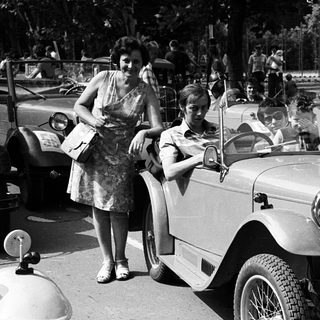 Vintage car rally with spectators and vintage vehicles.