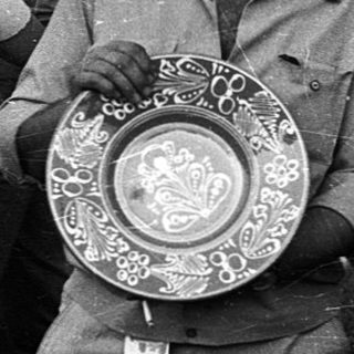 Four people holding trophies at an outdoor event.