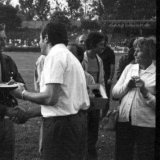 Handshake with medal presentation at outdoor sports event.