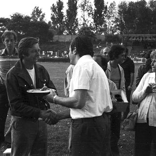 Handshake with medal presentation at outdoor sports event.