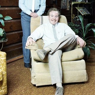 Two men in 1970s-style attire posing indoors.