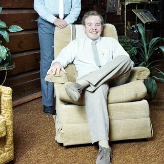 Two men posing indoors, one seated, one standing.