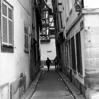 Narrow alleyway with couple walking, old European architecture.