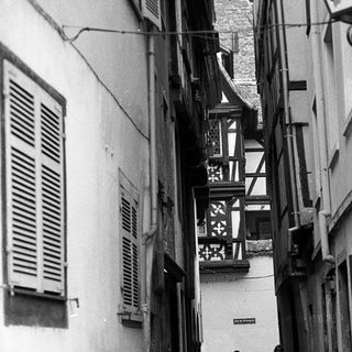 Narrow alleyway with couple walking, old European architecture.