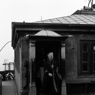 Woman in vintage coat exiting ornate building entrance.