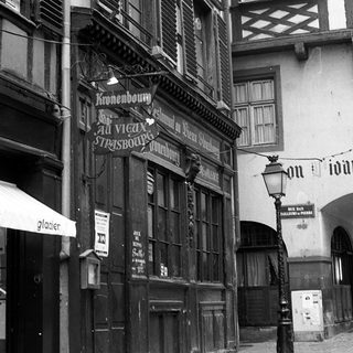 Historic European street with old timber-framed buildings and vintage signage.