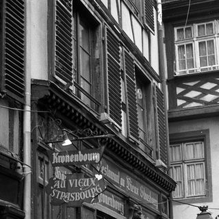 Historic European street with old timber-framed buildings and vintage signage.